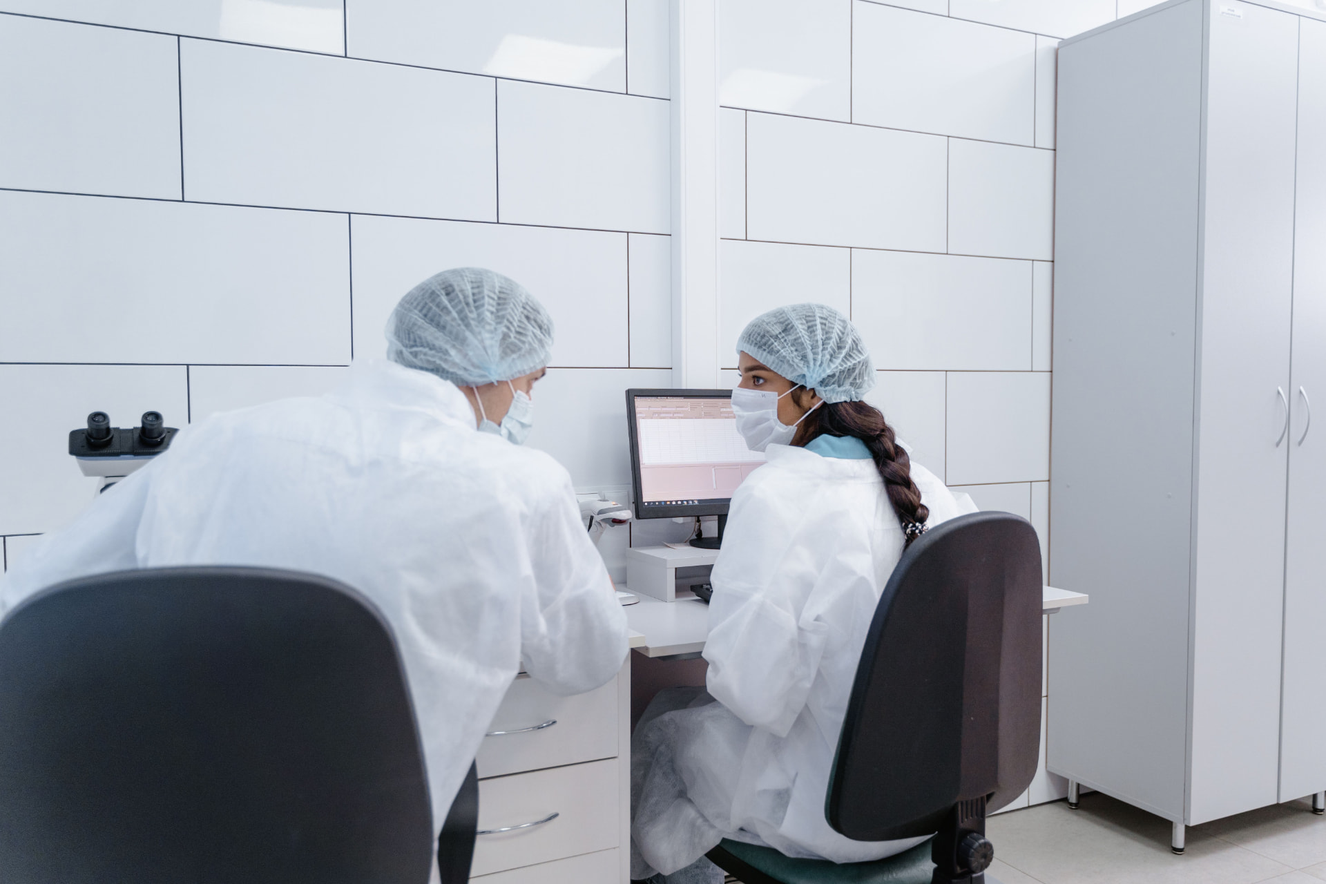Two laboratory researchers reviewing structured study data on a computer screen