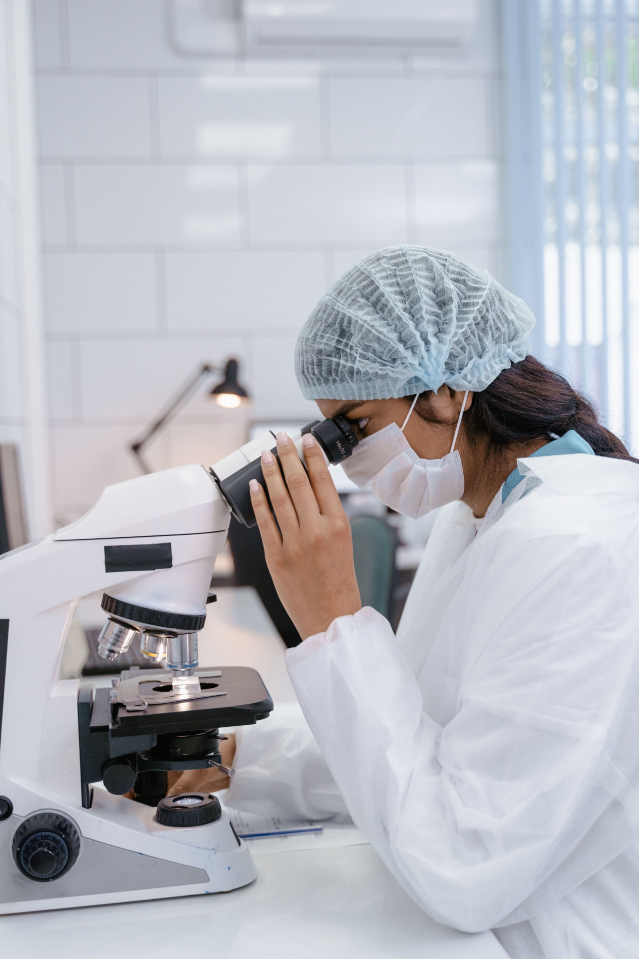 Laboratory researcher in protective clothing examining a sample under a microscope