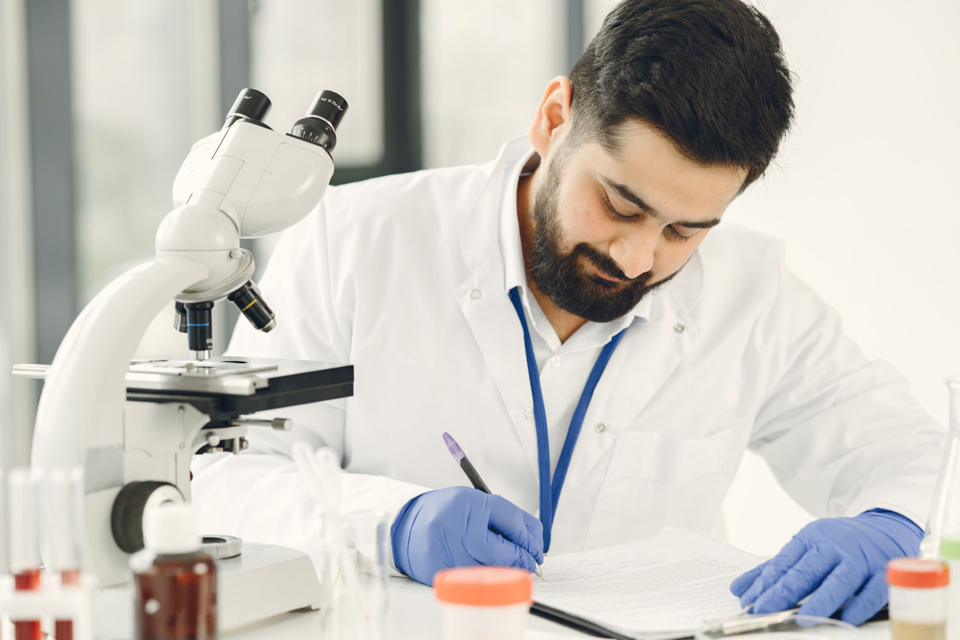 Laboratory researcher recording study documentation beside a microscope